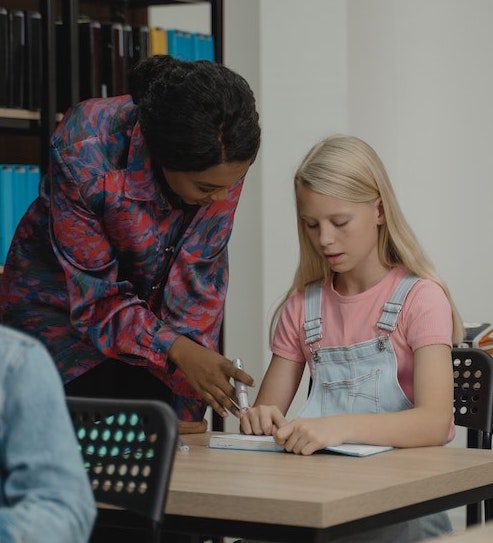 Teacher working with a student at a desk.