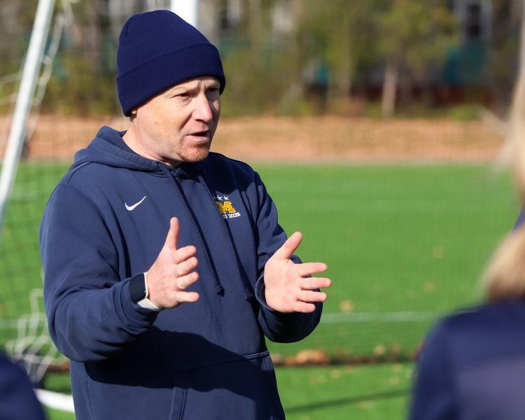 Steve Coaching a team wearing a beanie and blue sweatshirt.