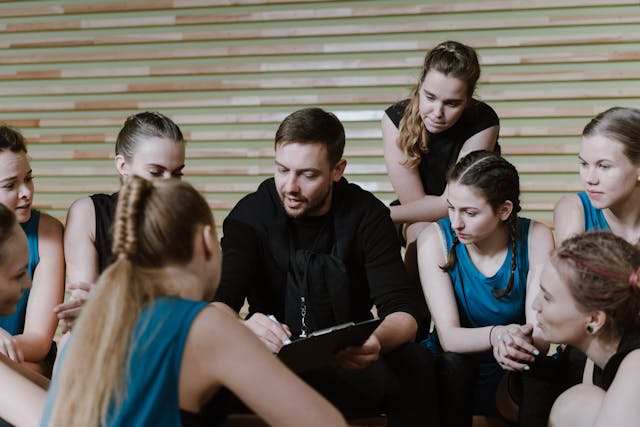 Coach talking to a group of players in a gym.
