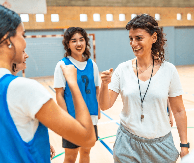 Two players and a coach on a court with the player and coach bumping fists.