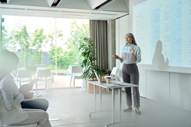 Woman standing in front of a screen giving a presentation.