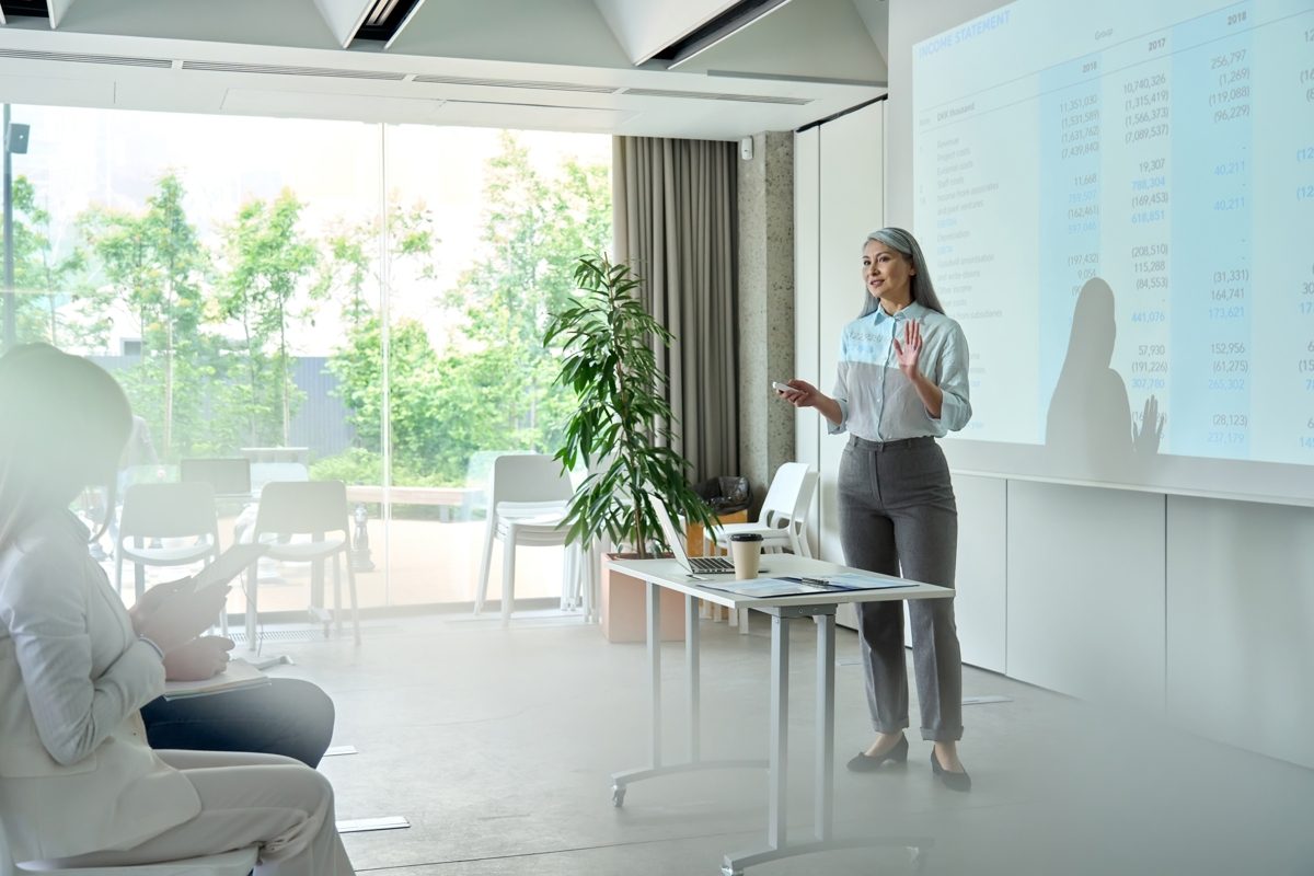 Woman standing in front of a screen giving a presentation.
