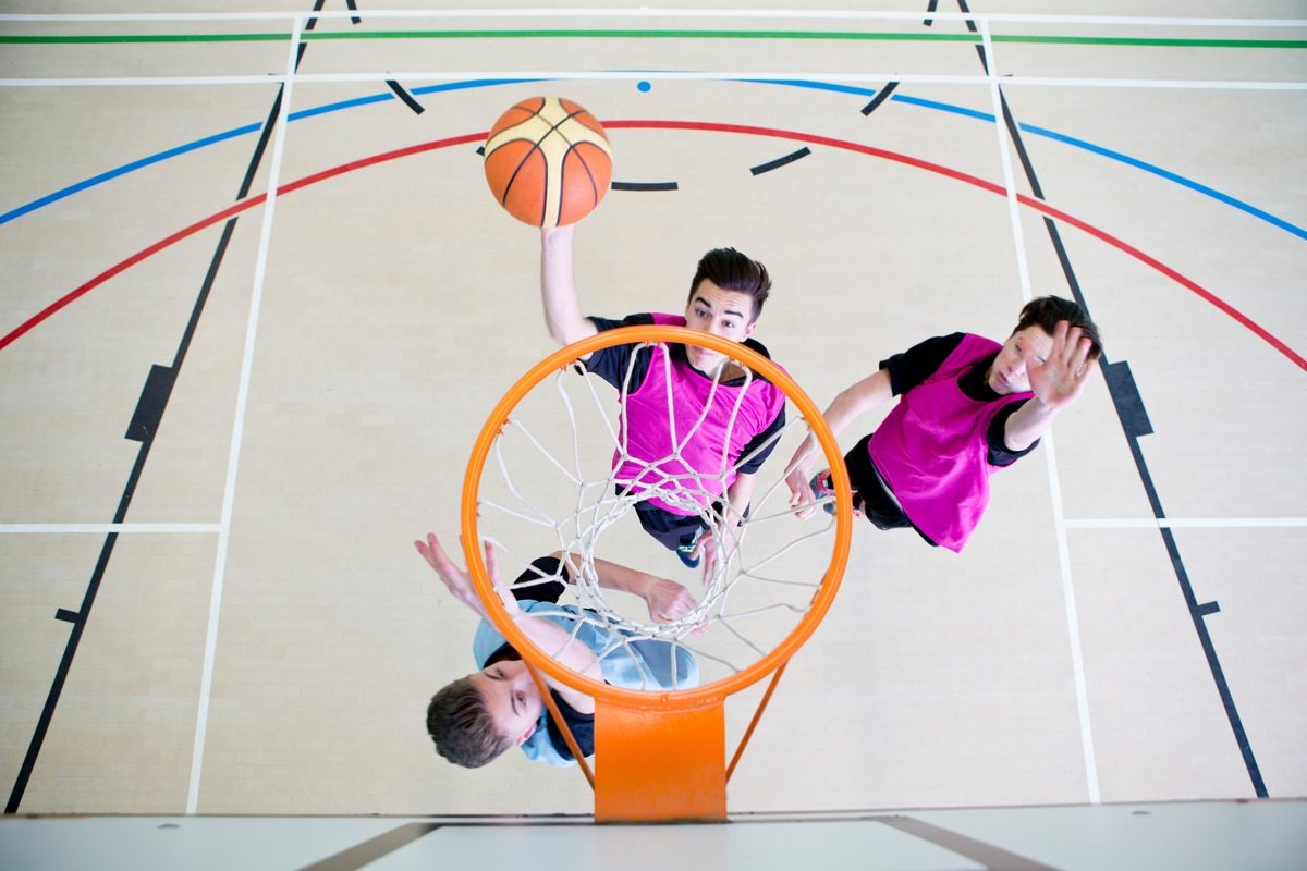 3 boys playing basketball by the rim.
